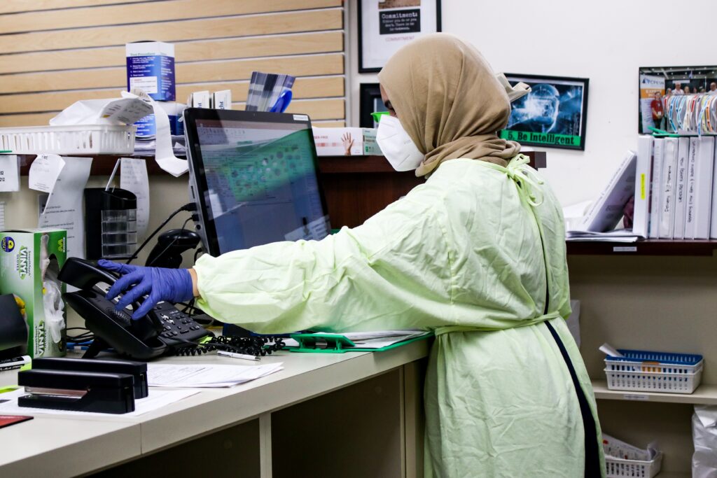 women in green protective robe answering call in healthcare clinic