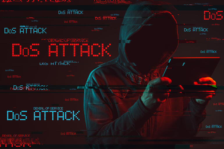 hooded person staring at tablet and background has the words "DoS attack"