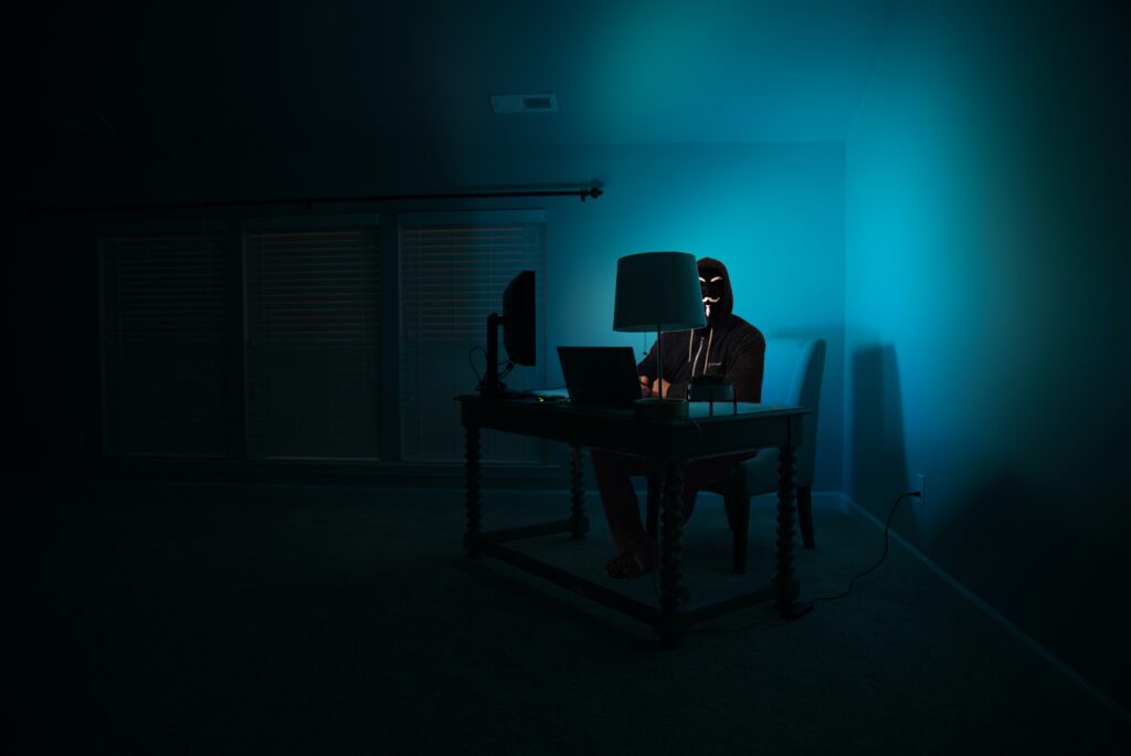 man sitting facing laptop in dark room
