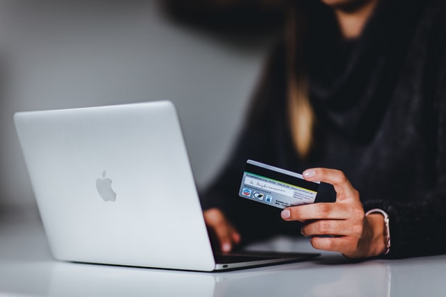 person sitting in front a laptop holding credit card