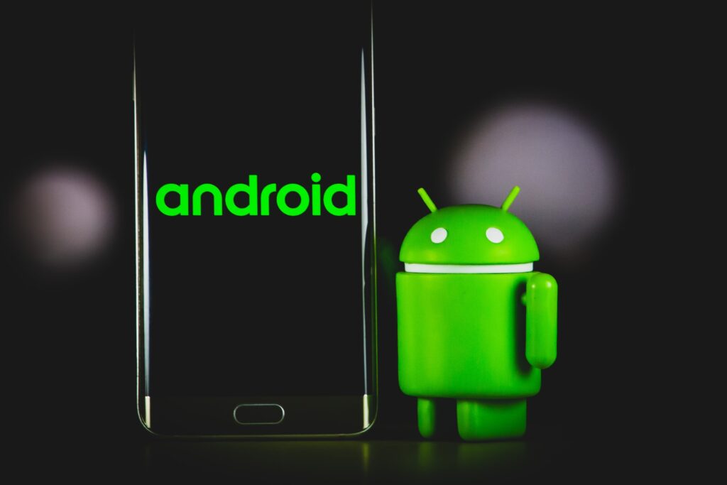 smartphone standing beside the green Android mascot