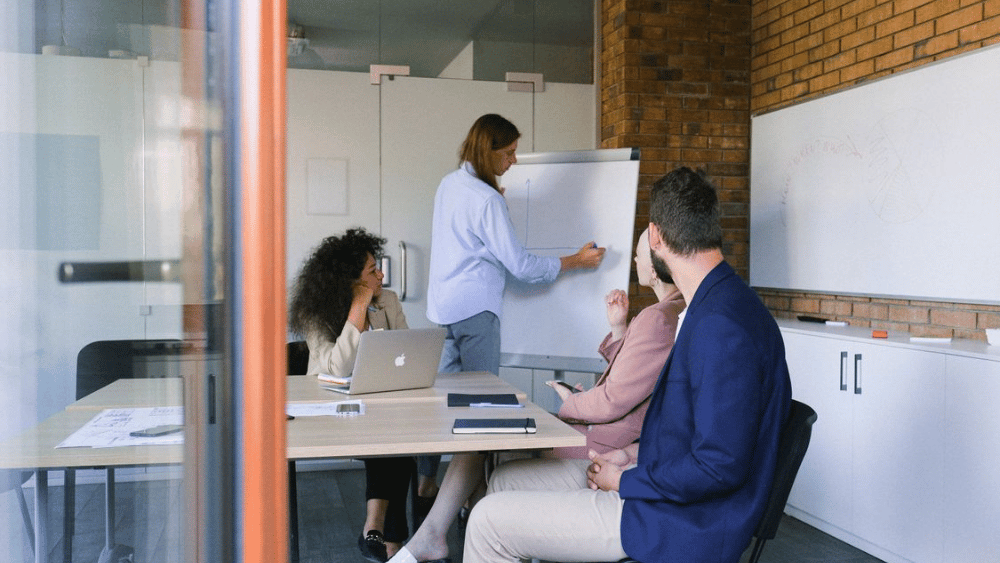 Team brainstorming in an office, writing on a whiteboard