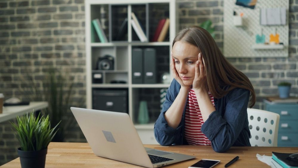 Woman at a desk looking at a computer stressed